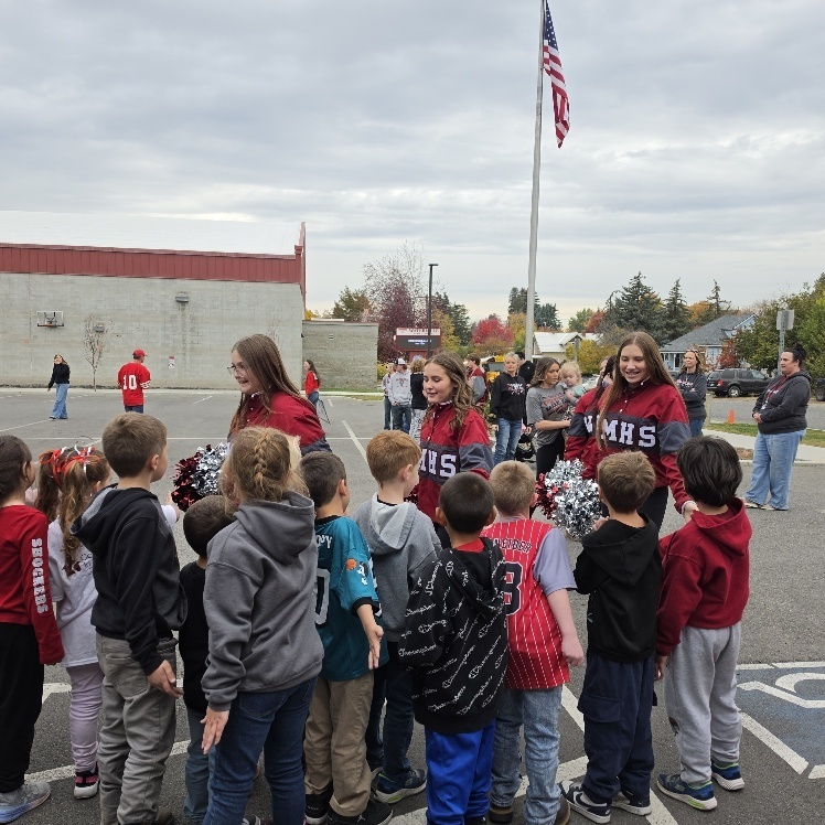 Cheerleaders giving high fives to younger students.