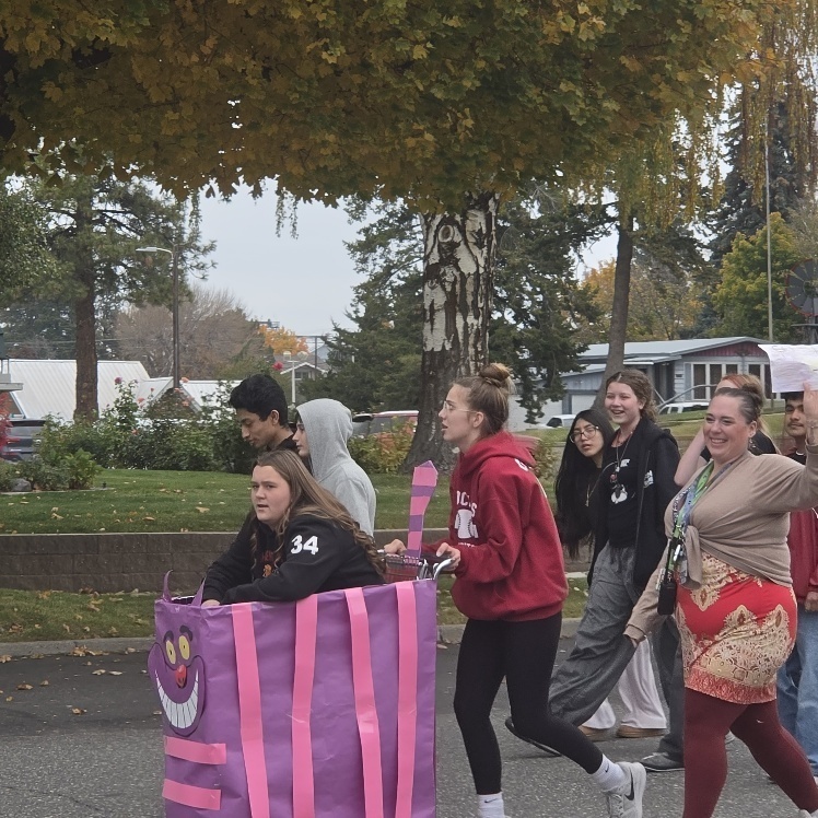 A student riding in a decorated shopping cart.