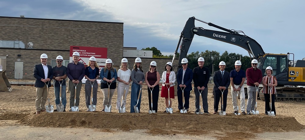 School staff members standing at construction site with shovels for groundbreaking ceremony