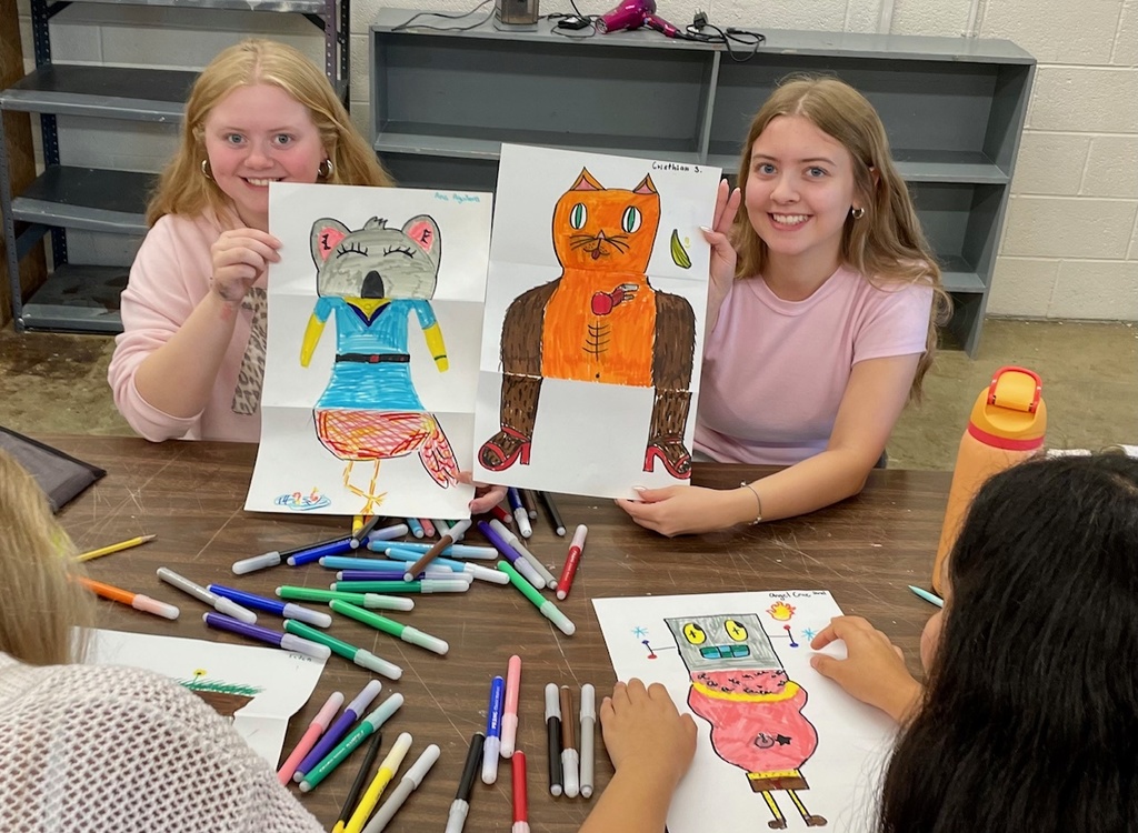 female students with their folded paper drawings