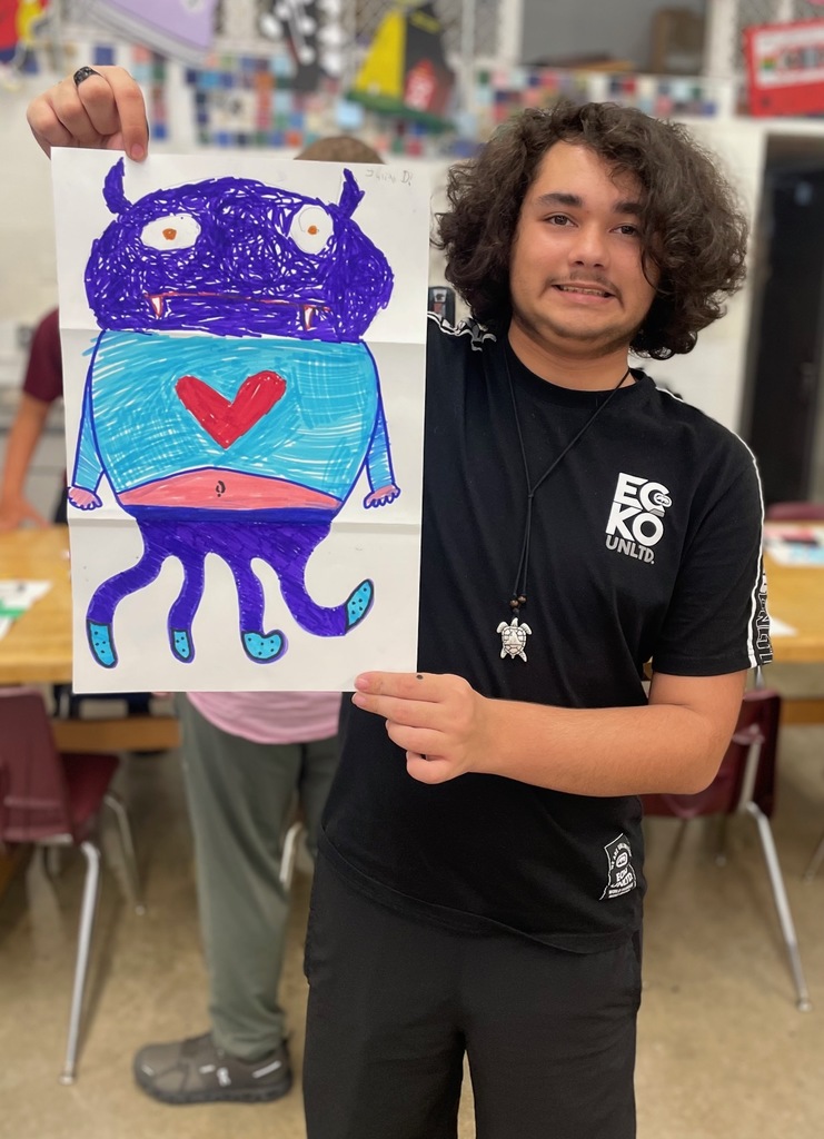 male student showing his folded paper drawing