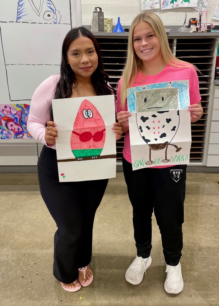 female students showing their folded paper drawings