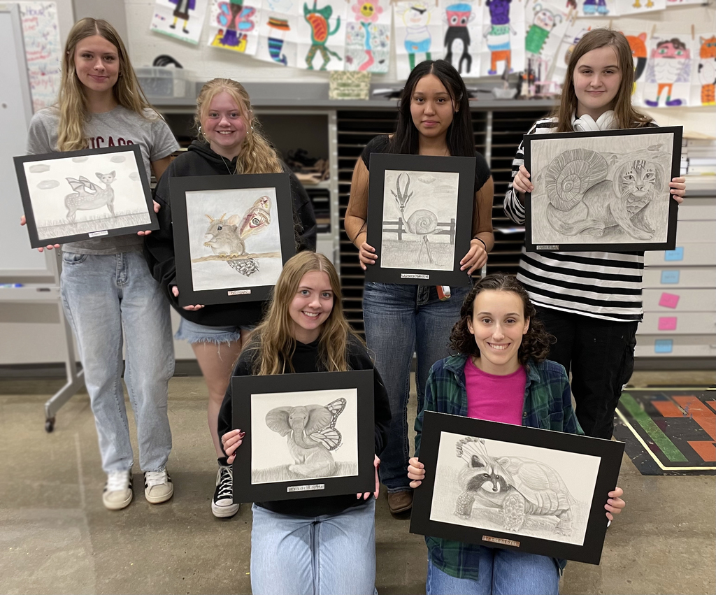 Girls holding their pencil drawings 