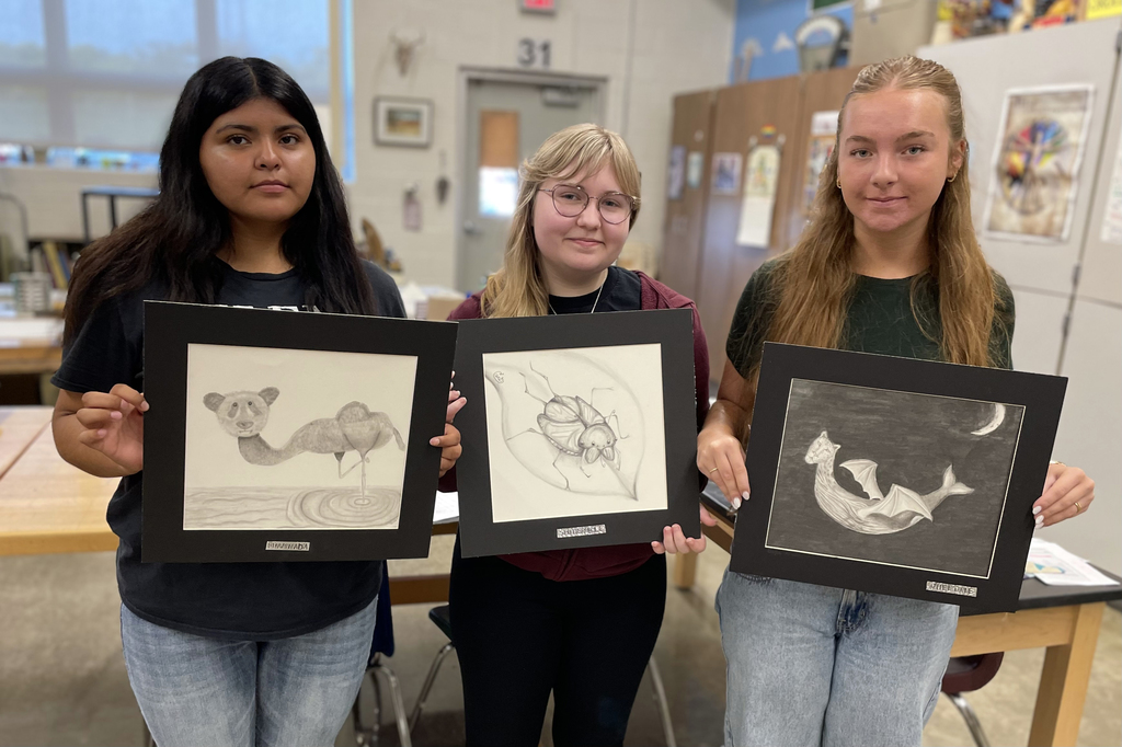 girls holding their animal pencil drawings 