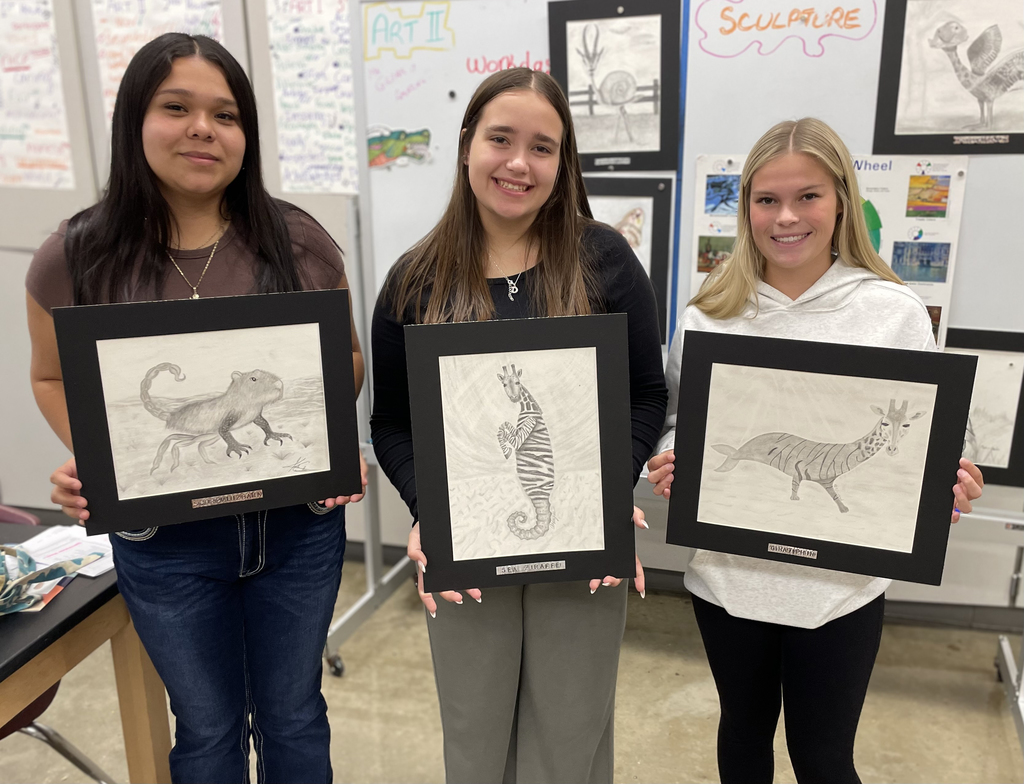 Girls holding their animal pencil drawings 