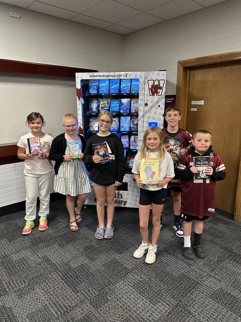 kids standing in front a book vending machine holding books