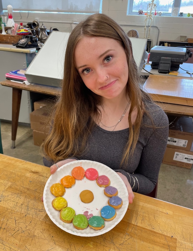 student holding her color wheel made from frosting on vanilla wafers on a plate