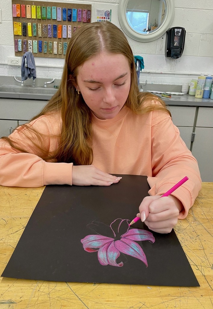 female student working on her colored pencil floral drawing