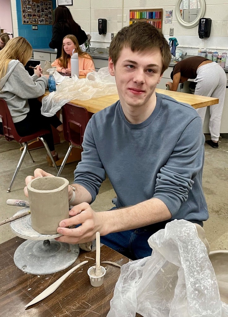 male student shaping clay project 