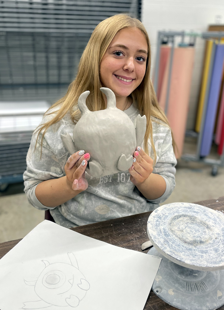 female student holding her clay project