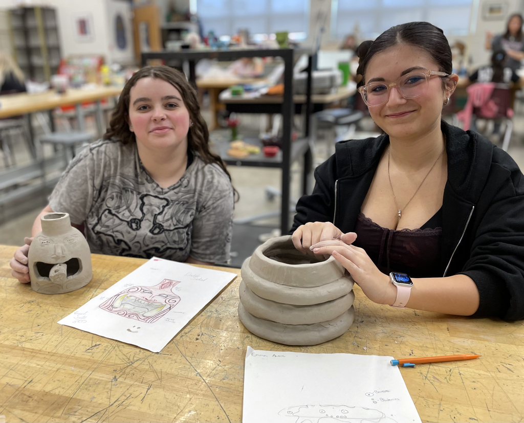2 female students showing their pottery projects