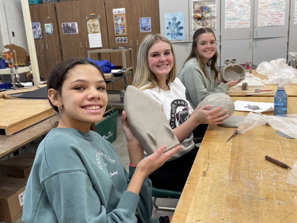 3 female students holding their clay projects