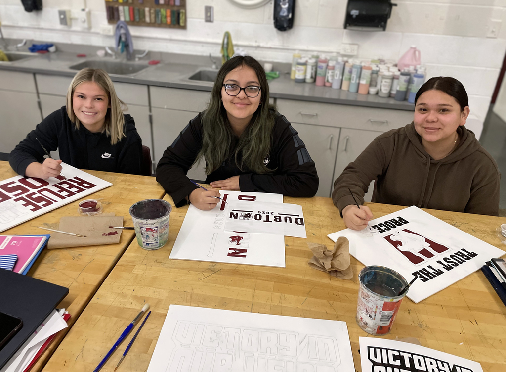 female students painting letters for wall mural