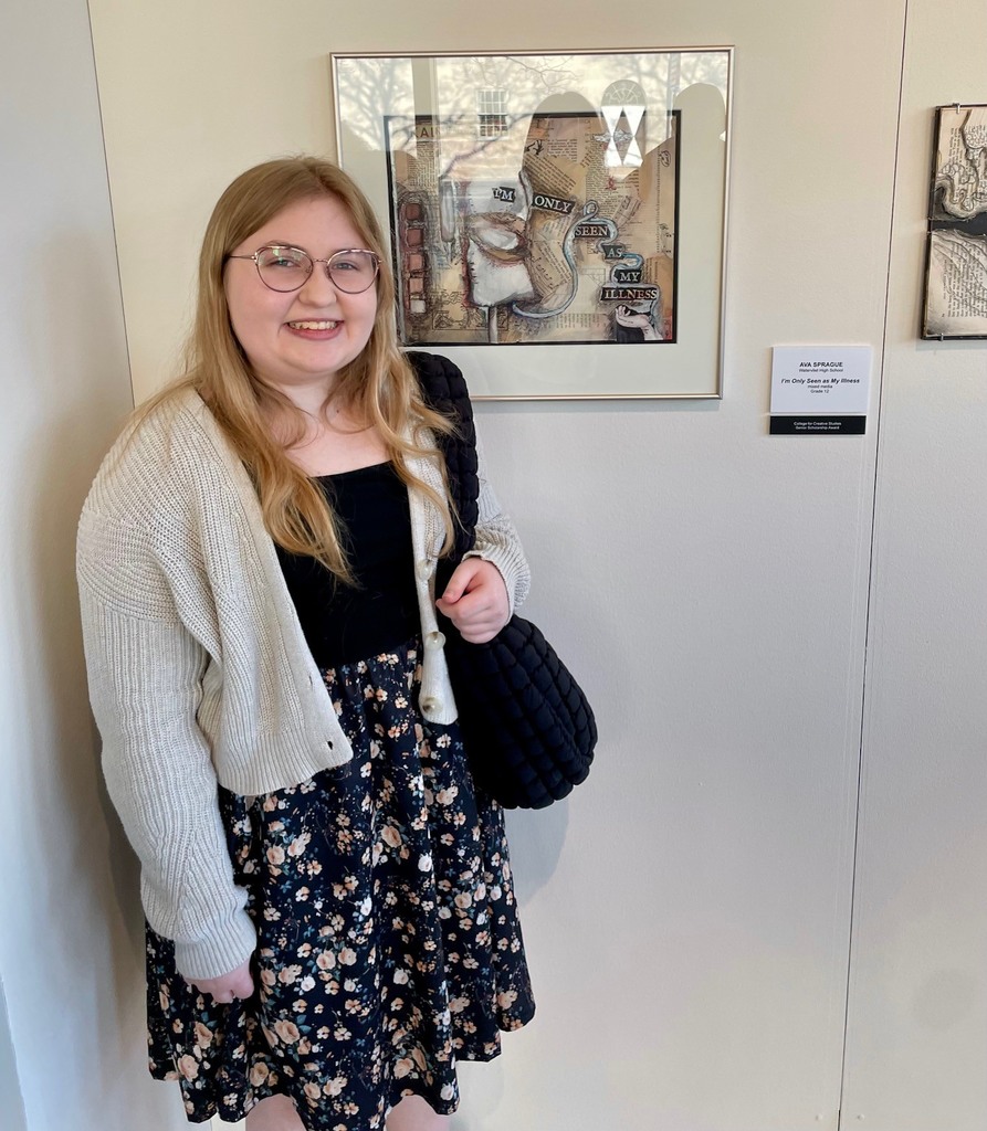 female student next to her mixed media framed project, "I'm Only Seen as My Illness".