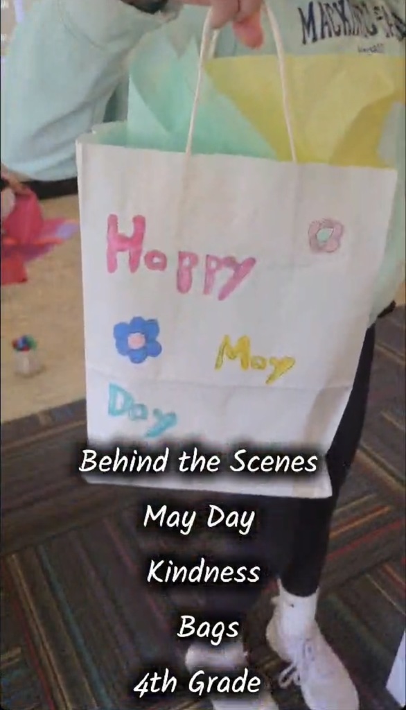 child holding gift bag that says "happy may day" with flowers