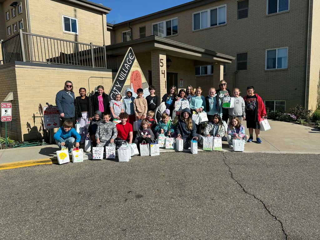 group of people standing in front of a building with gift bags