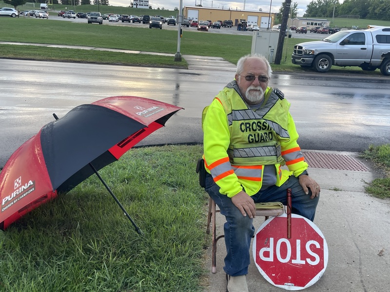 the school crossing guard seated with stop sign
