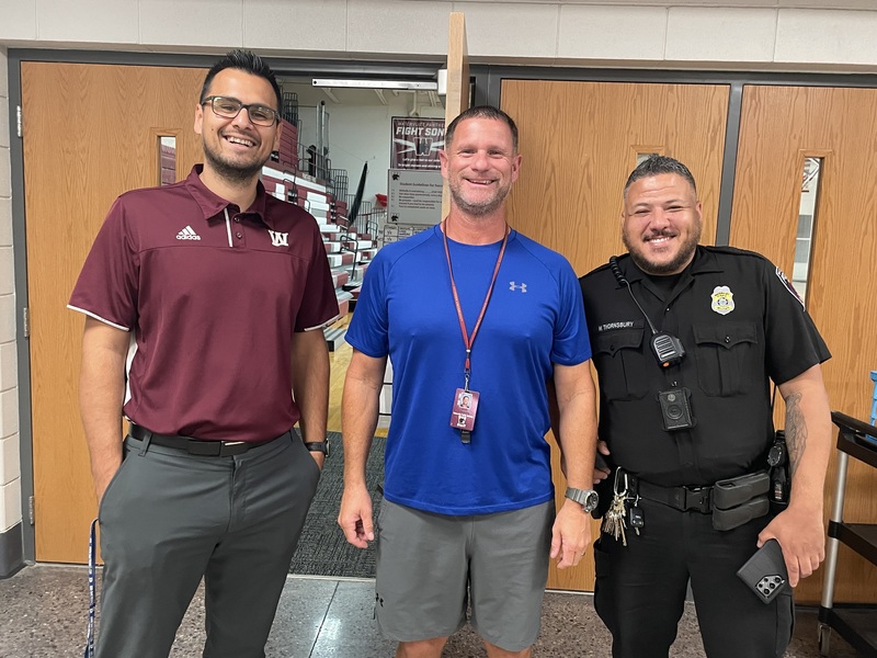 Athletic Director, Gym Teacher, and School Resource Officer standing in front of the gym doors