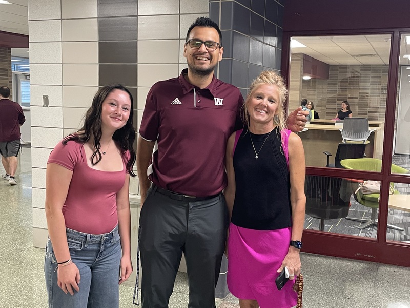 a female student, the athletic director and principal smiling