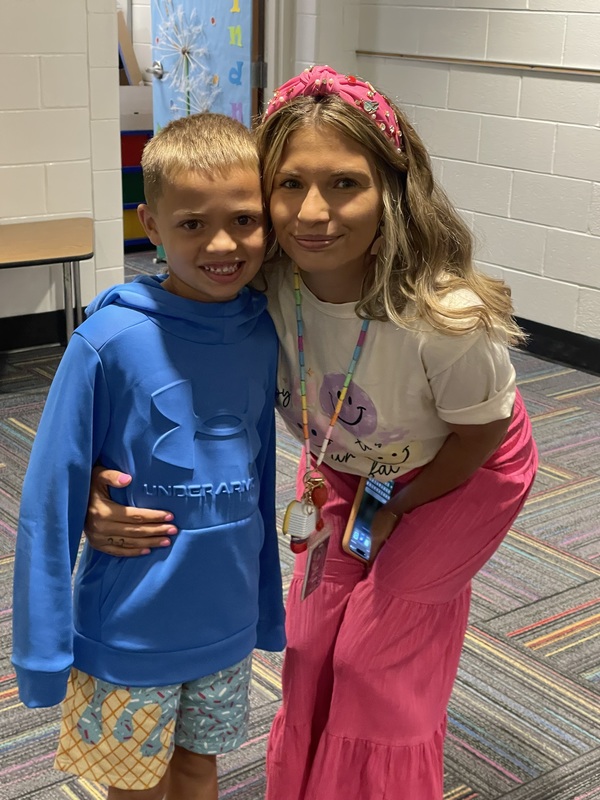 female adult with arm around a young boy 