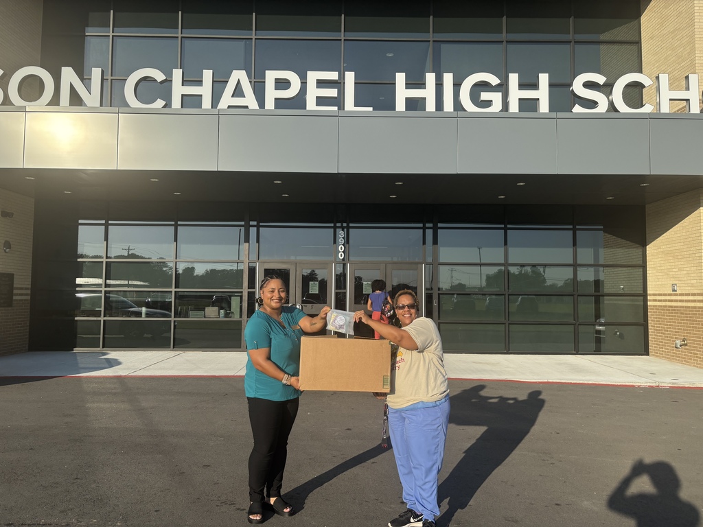 Two people are outside a building with a sign that reads "SON CHAPEL HIGH SCH." They are carrying a cardboard box.