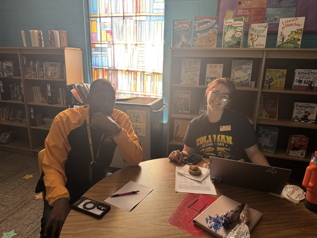 Two people sitting at a table, one with a calculator and the other with a laptop.