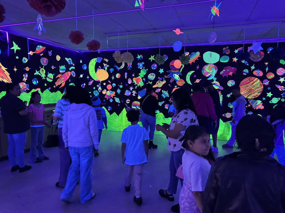 Students in a dark room with glowing decorations on the walls