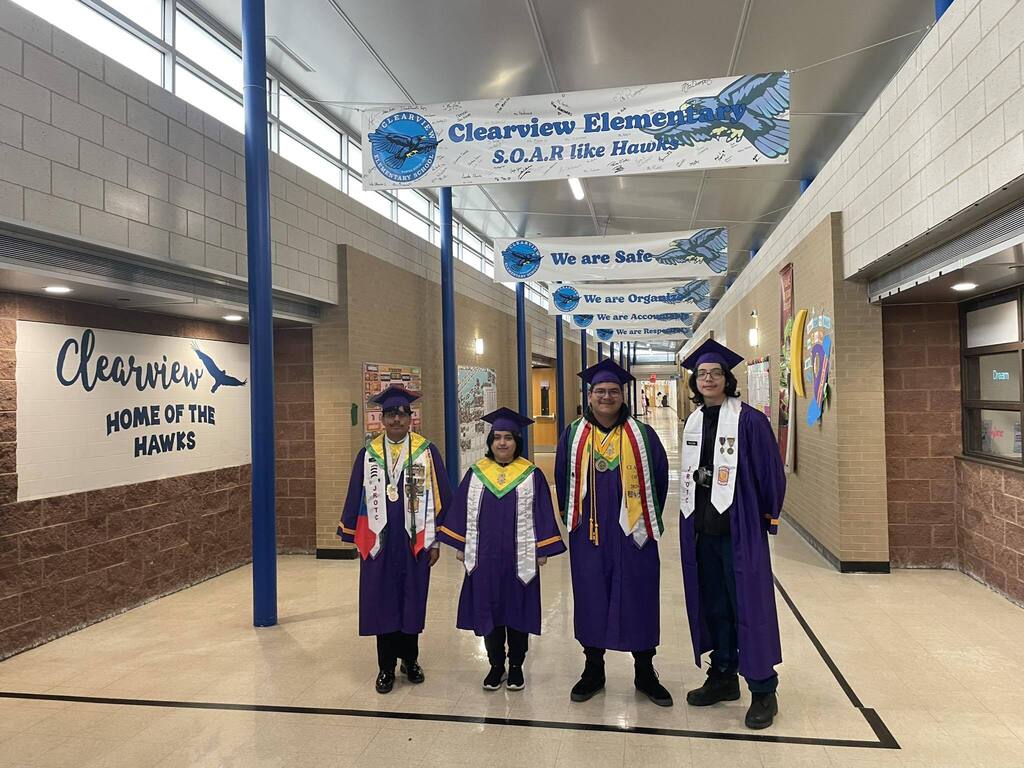 Four high school students wearing their purple cap and gown