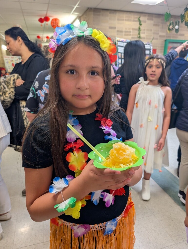 A student in traditional Hawaiian attire holds a treat during the AAPI Heritage Month celebration