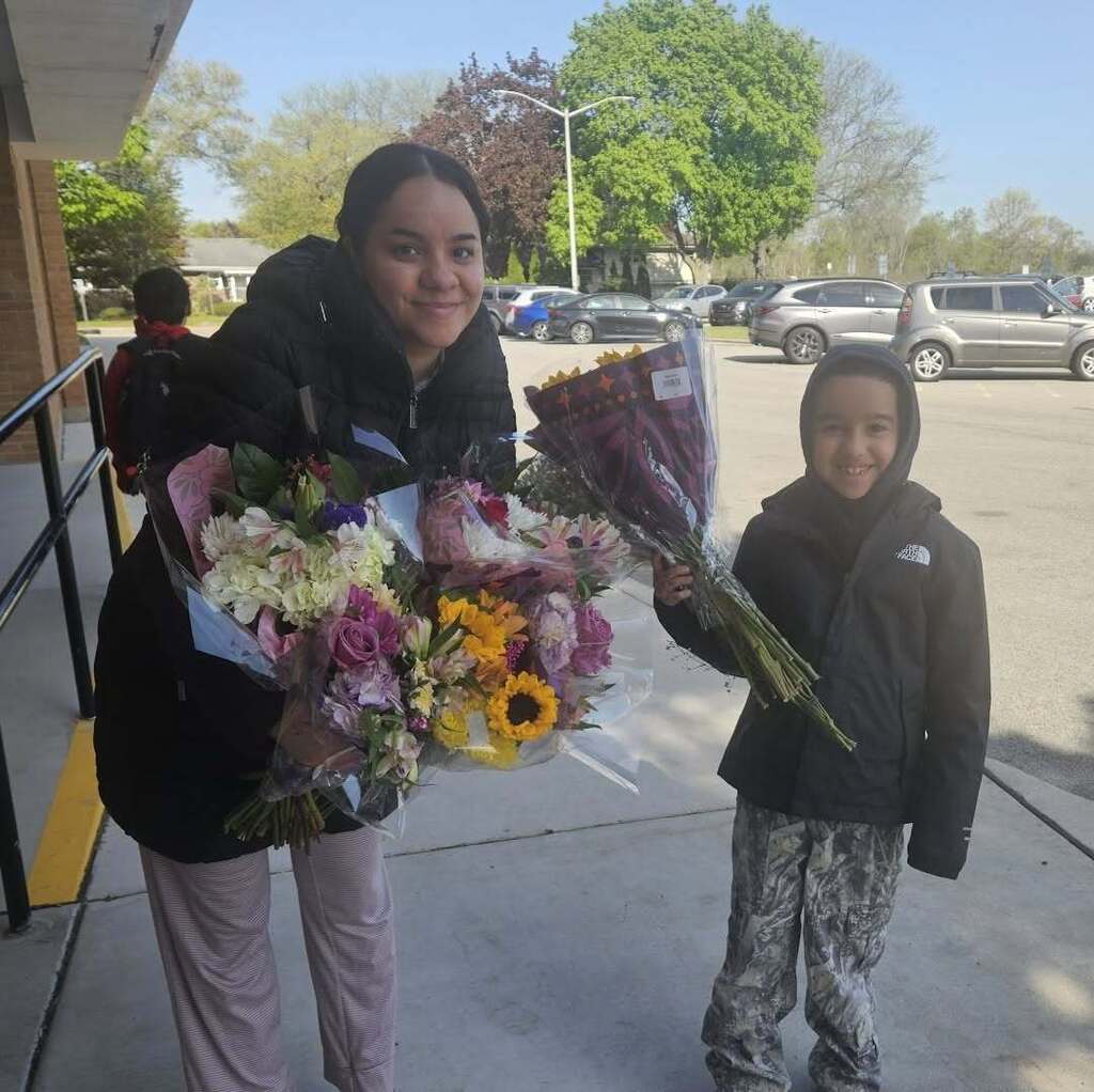 Teacher holding a bouquet of flowers next to a student