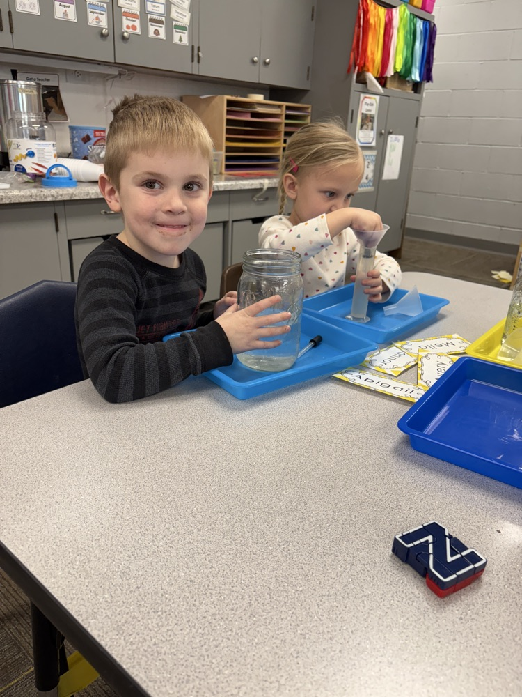 children using eye droppers to transfer water from one container to another