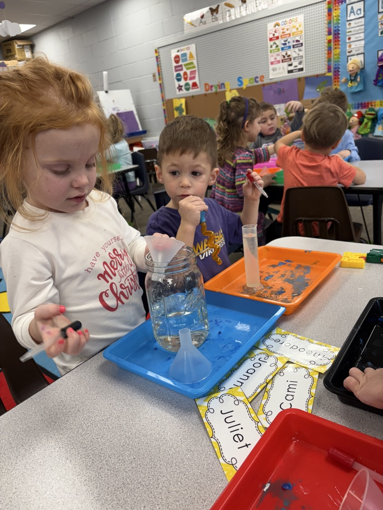 children using eye droppers to transfer water from one container to another