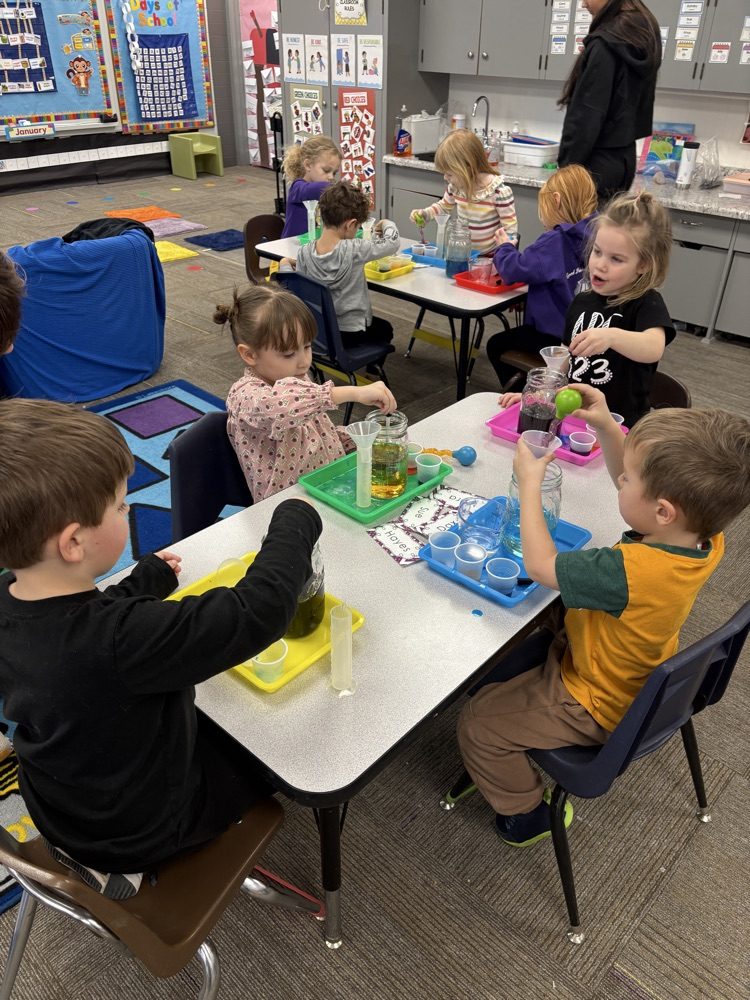 children using eye droppers to transfer water from one container to another