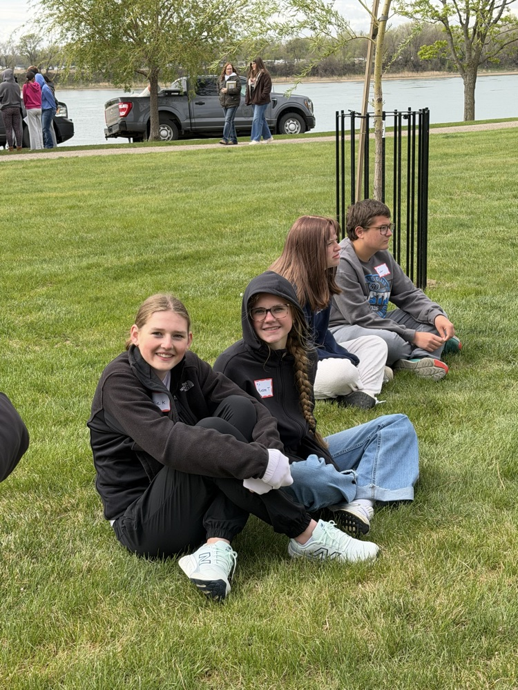 girls sitting in the grass listening about endangered birds 