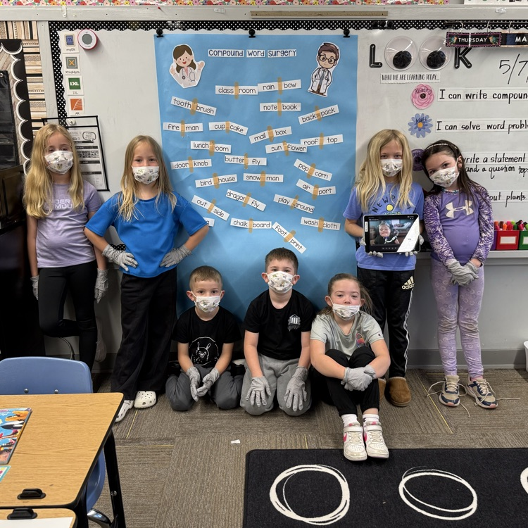 first grade students in masks and gloves are pictured with the compound word wall