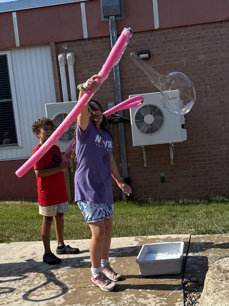 Students use a bubble wand to make giant bubbles.