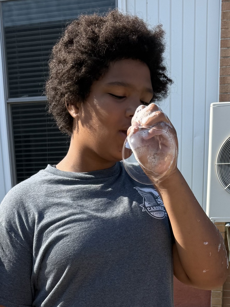 Students use a bubble wand to make giant bubbles.