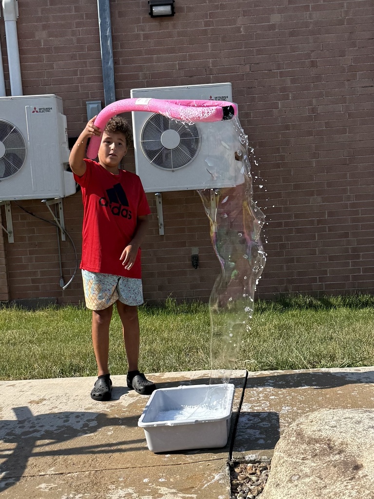 Students use a bubble wand to make giant bubbles.
