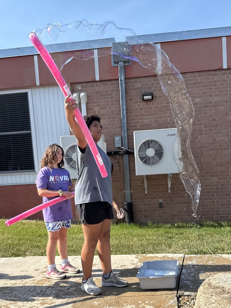 Students use a bubble wand to make giant bubbles.