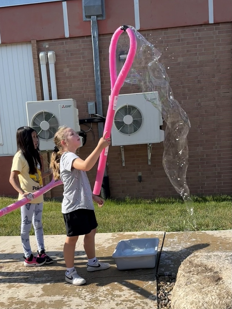 Students use a bubble wand to make giant bubbles.