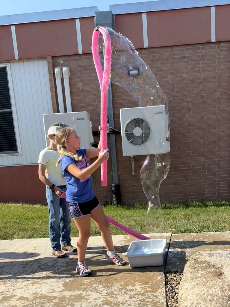 Students use a bubble wand to make giant bubbles.