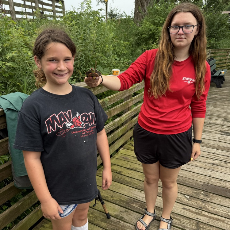 student caught a turtle. the instructor is helping the student by holding the turtle