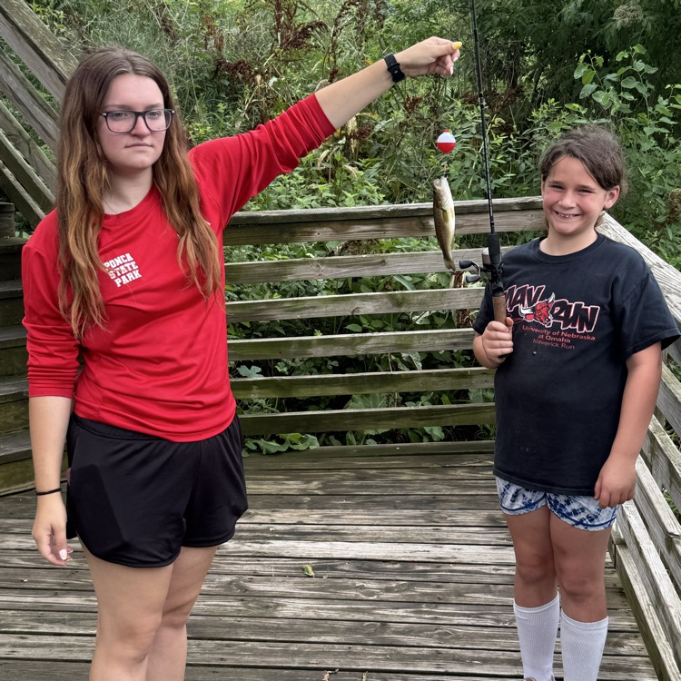 student caught a fish. the instructor is helping the student by holding the fish