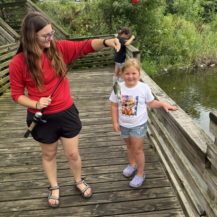student caught a fish. the instructor is helping the student by holding the fish