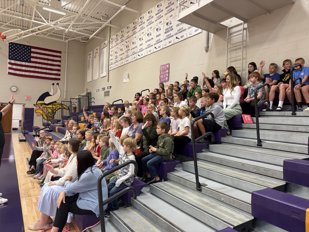 The elementary kids are excited and are raising their hands to volunteer to help Rob Holla at the assembly.
