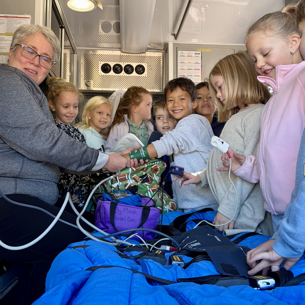 1st grade students sit in the ambulance and watch the demonstration.