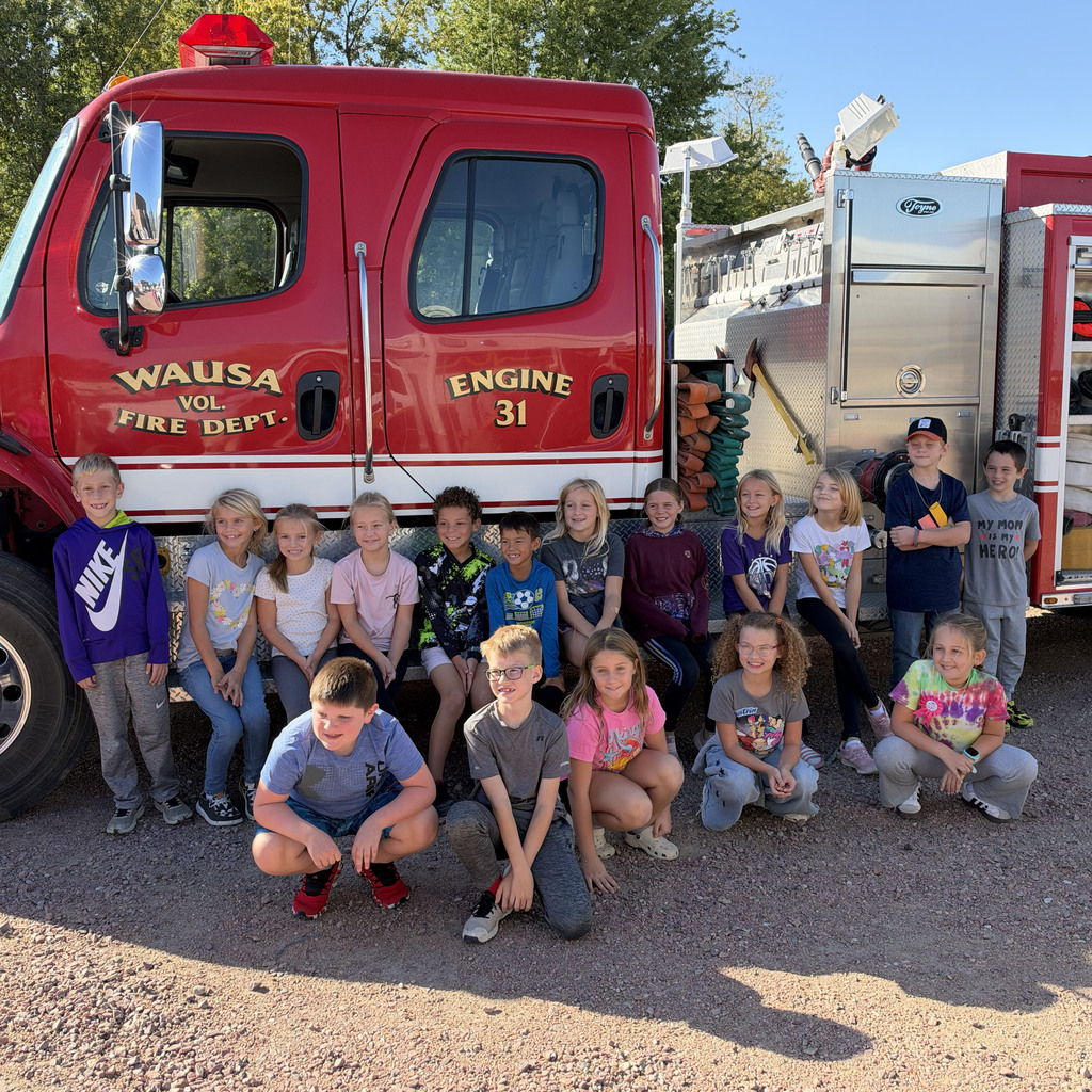 The third grade class poses in front of the fire truck.