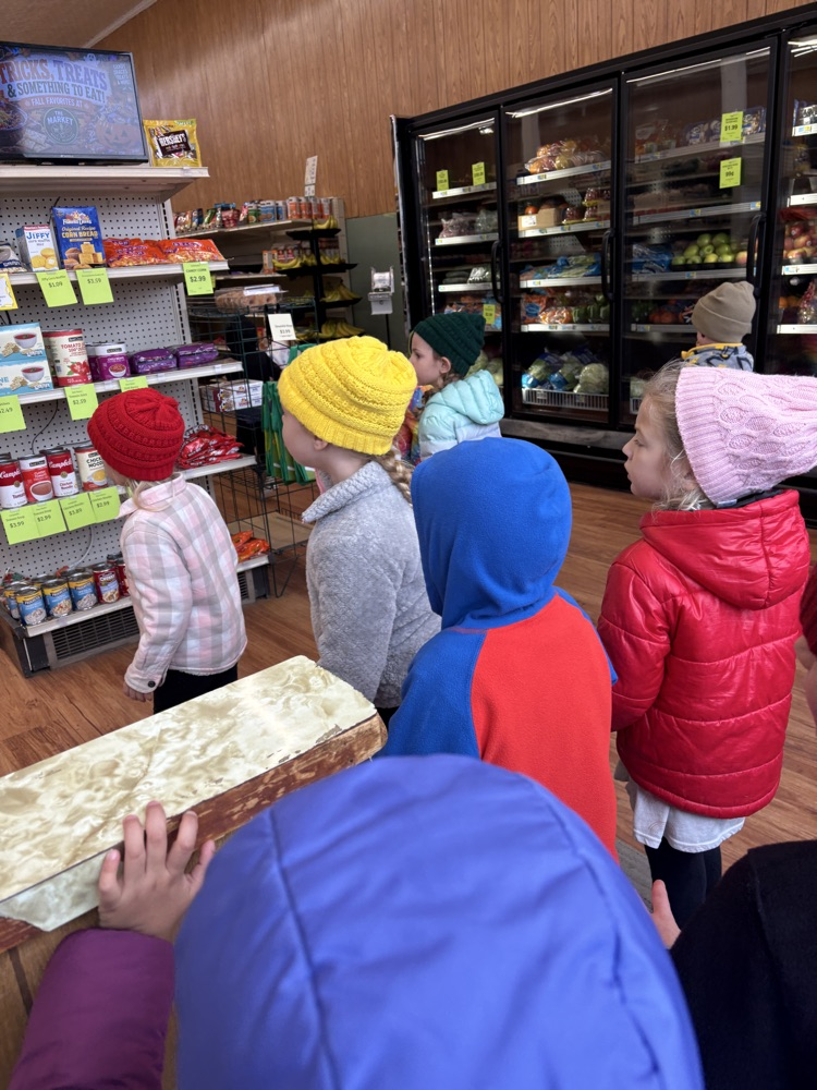 PreK students are in the town grocery store looking at the shelves for the letter G puppet 