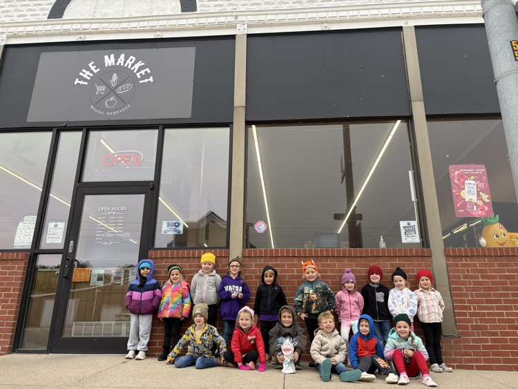 PreK students gathered together in front of the grocery store building with the letter G puppet