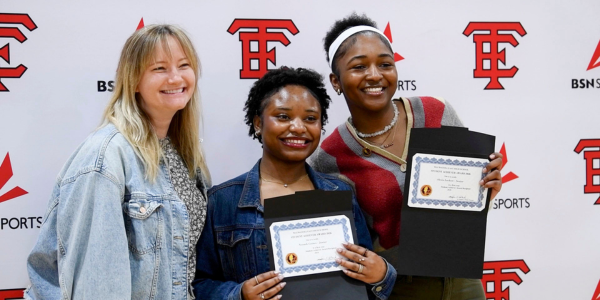 Students holding certificates smiling with teacher